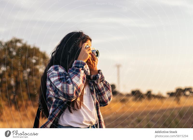 Young woman taking photos with analog camera in the field at sunset lifestyle young girl photography vintage retro travel hipster photographer beautiful people