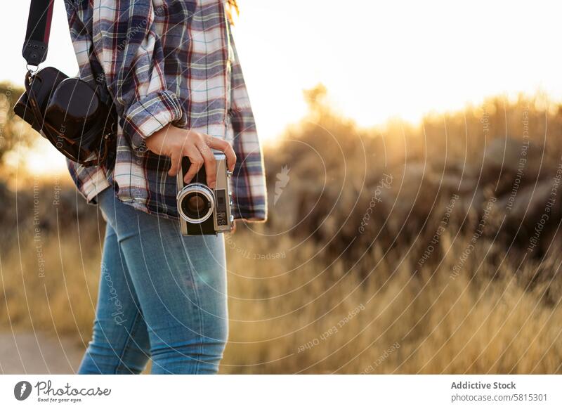 Unrecognizable woman taking photos with analog camera in the countryside lifestyle young girl photography vintage retro travel sunset hipster photographer