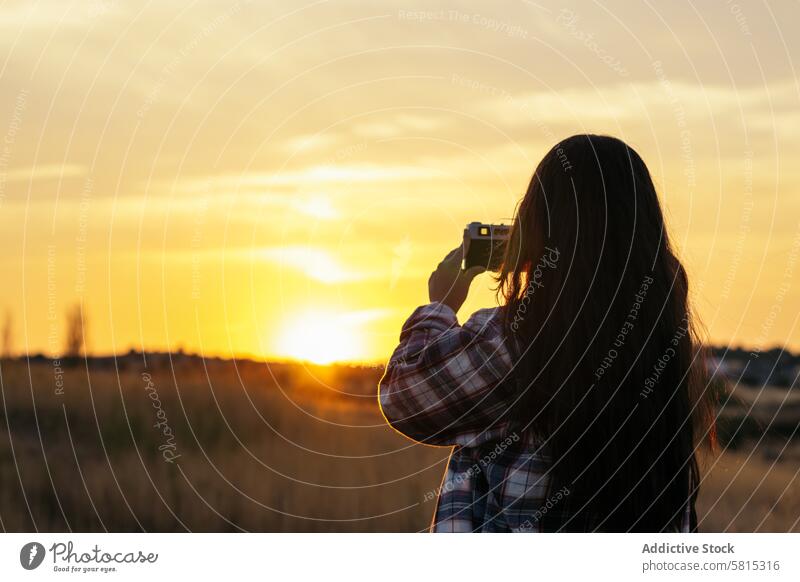 Young woman taking photos with analog camera in the field at sunset lifestyle young girl photography vintage retro travel hipster photographer beautiful people