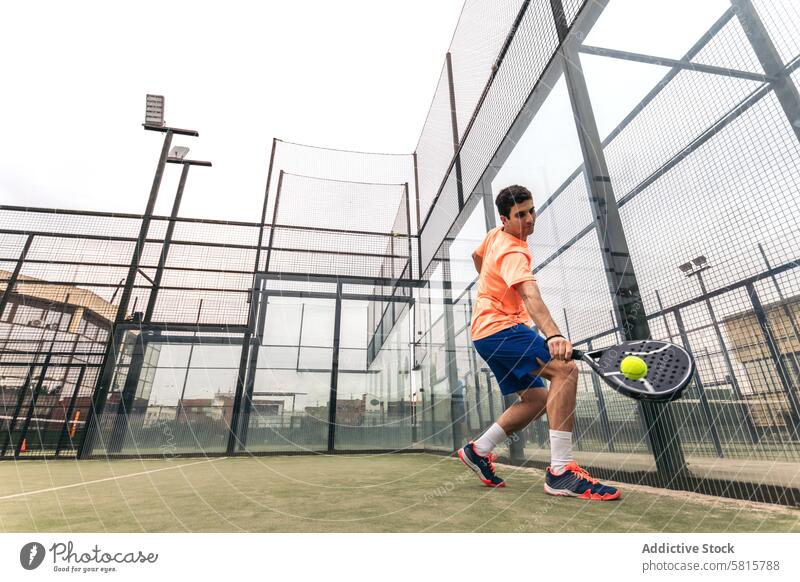 young man playing paddle tennis. low angle sport court recreation racket game lifestyle male player leisure action serve net healthy adult ball active men