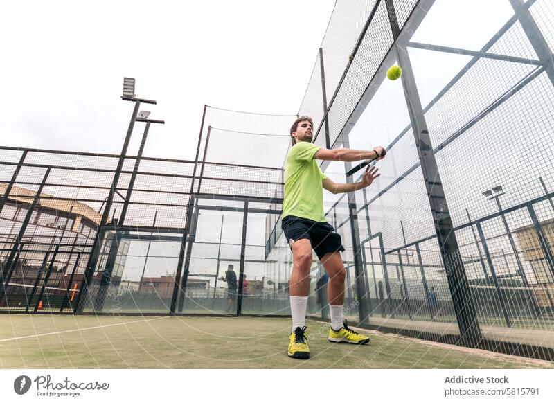 young man playing paddle tennis. low angle sport court recreation racket game lifestyle male player leisure action serve net healthy adult ball active men