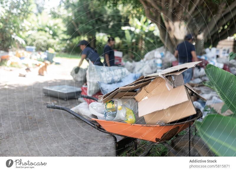 Packed Wheelbarrow of Plastics and Cardboard with Background Workers packed Recycling Laden Activities Blur Engaged Loaded Focus Environment Sustainability