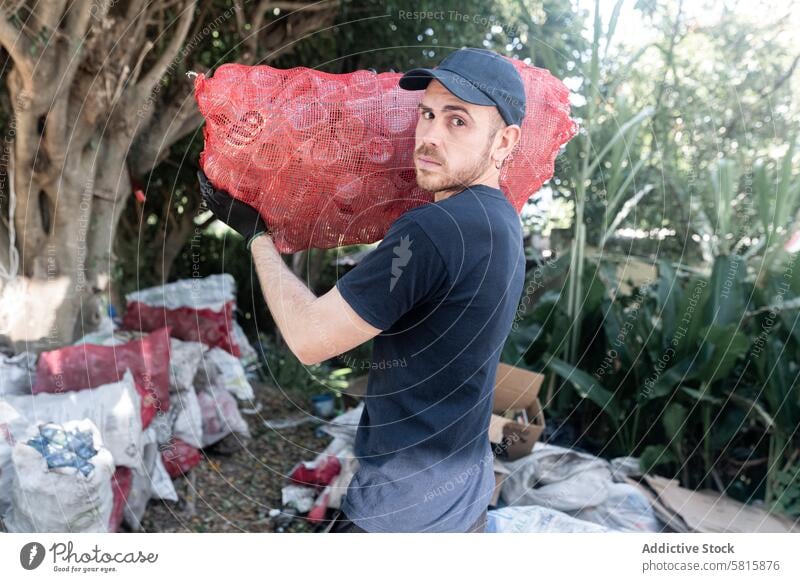 Young Caucasian Man Handling Glass Recycled Bottles at Recycling Facility. Serious attitude Sack facility Attitude Commited Camera plant Portrait Holding