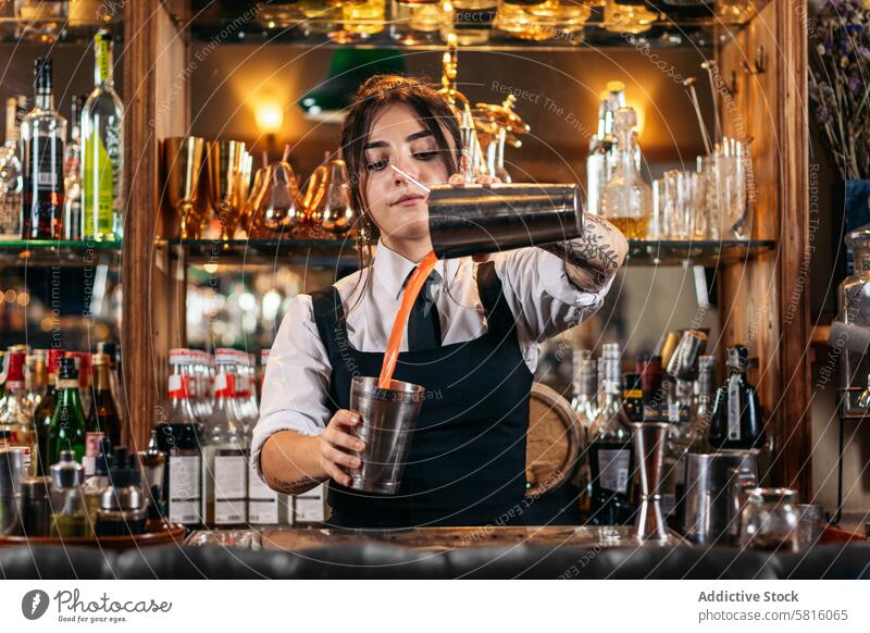 Female bartender preparing a cocktail in a traditional cocktail bar barwoman beverage mixologist nightclub alcohol barkeeper glass drink work professional
