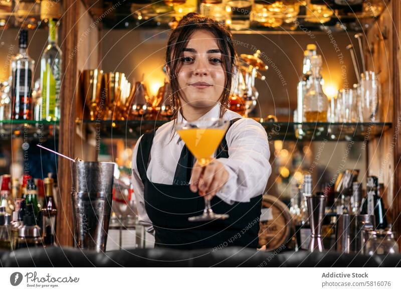 Young female bartender offering a drink cocktail barwoman beverage mixologist nightclub alcohol barkeeper glass work professional bartending indoors jigger job