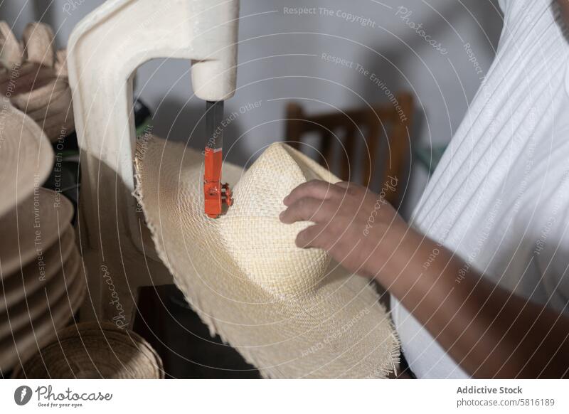 Making a hole in a natural fiber hat decorating rope palm tree man adult Hispanic brunette measure millinery tailor drilling workshop process production