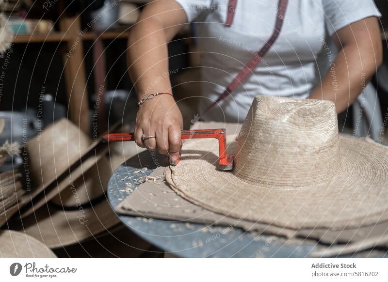 Cutting the brim of a traditional natural fiber hat measuring palm tree tape measure woman adult Hispanic crafting millinery tailor workshop process production