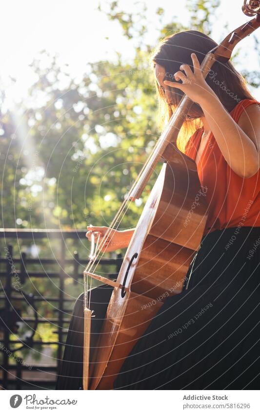 A young woman playing the cello on an outdoor stage musician instrument concert performance artist musical outdoors classical violin violinist entertainment