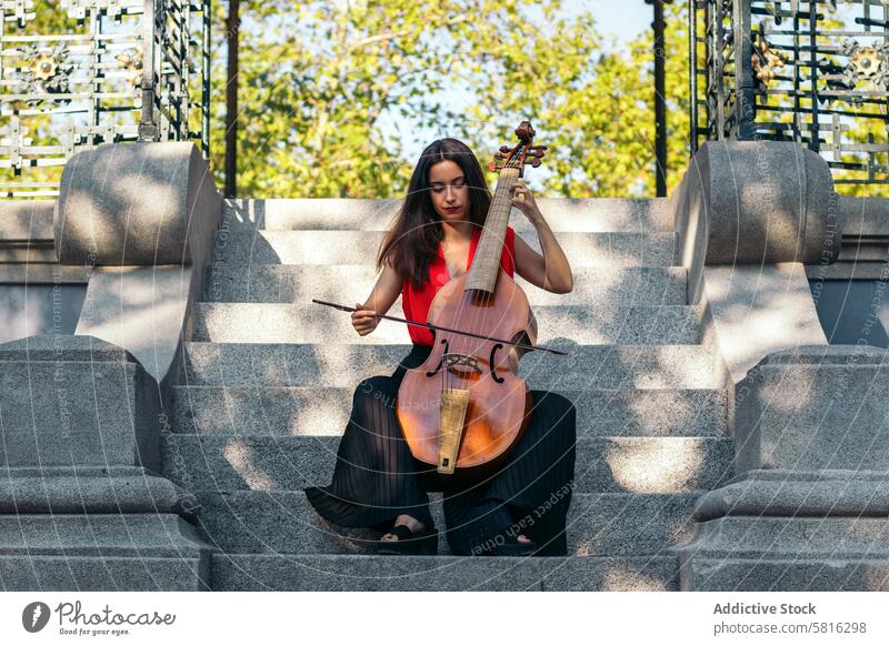 A young woman playing the cello outdoors musician instrument concert performance artist musical classical entertainment orchestra melody symphony sound