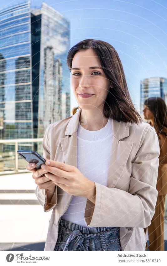 A woman dressed in business attire is standing outside with a cell phone in her hand and about to use it Beautiful People Modern attractive beautiful beauty