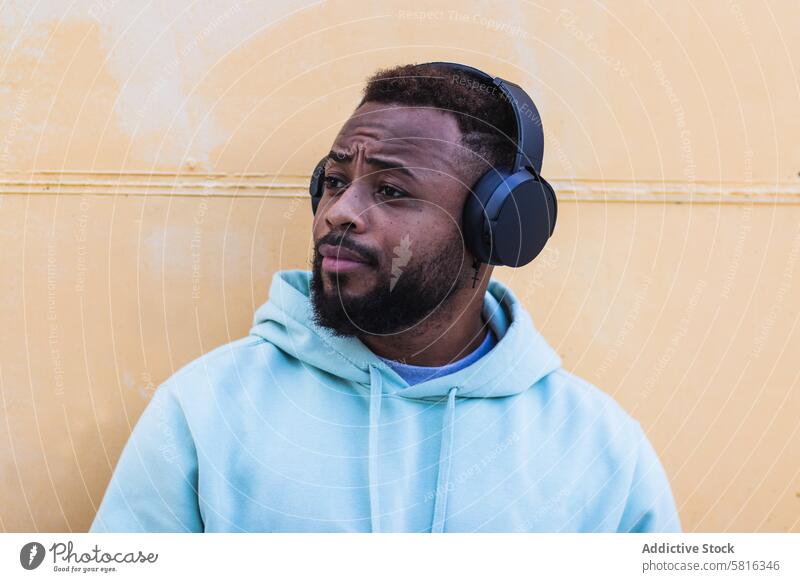 Optimistic black hipster listening to music with headphones man enjoy beard wireless adult african american ethnic male optimist casual device sound gadget