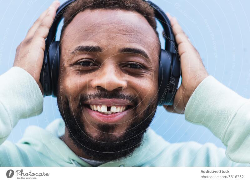 Optimistic black hipster listening to music with headphones man happy enjoy cheerful beard wireless adult african american ethnic male optimist casual device