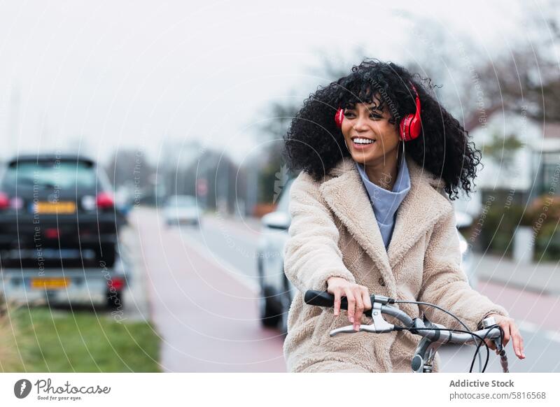 Excited black woman in headphones riding bicycle using music listen road car ride bike chill city female portrait african american woman street smile positive