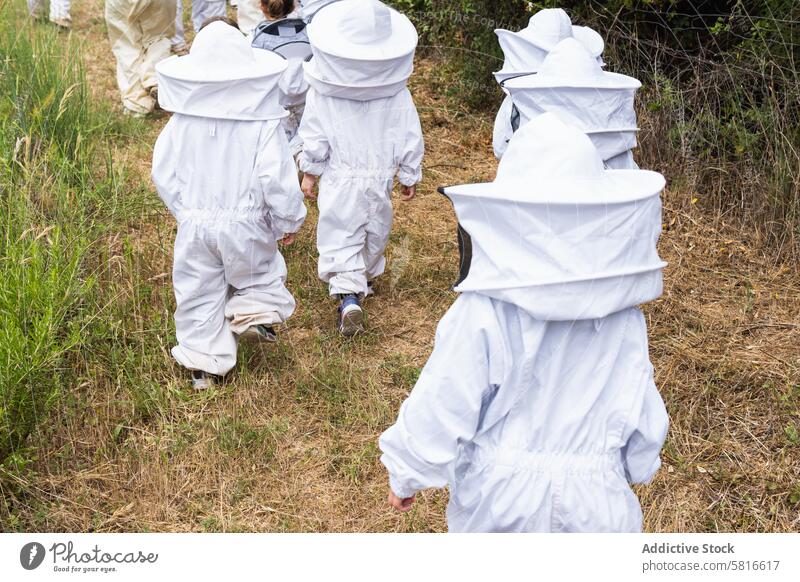 Company of kids in protective costumes in apiary children beekeeper together company garden safety countryside glove rubber village adult professional nature