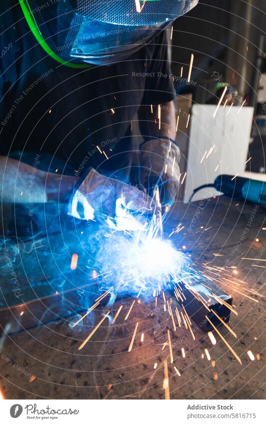 Welder in protective helmet welding metal detail in workshop spark man metalwork machine workbench male instrument tool piece professional master skill