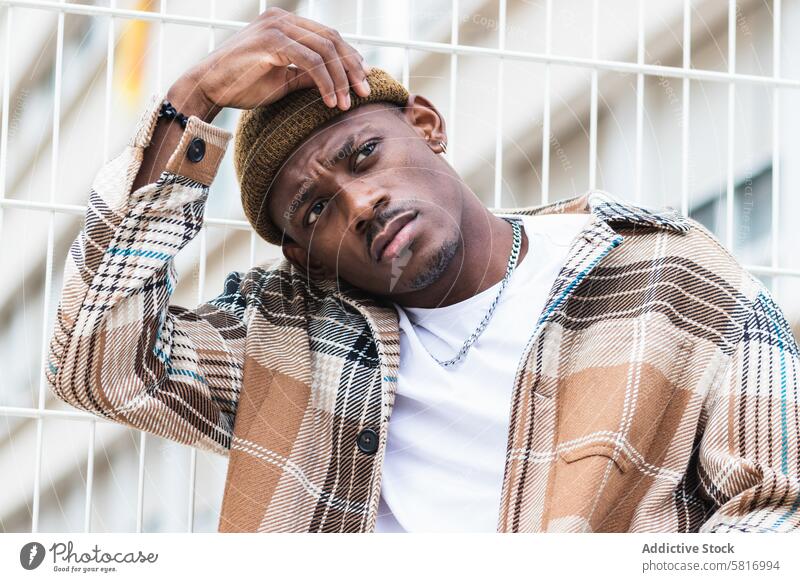 Trendy African American guy on city street man lean fence style outfit urban modern young male black ethnic african american trendy casual cool hipster