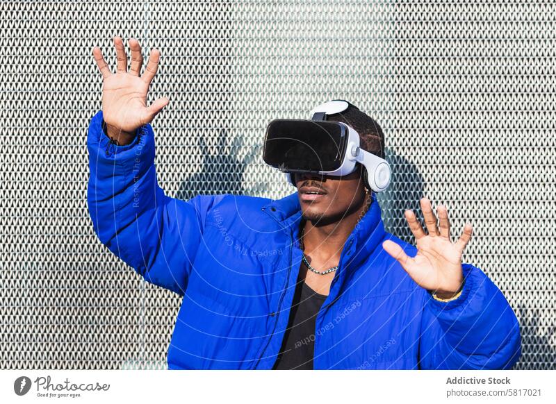 Black man experiencing virtual reality in city goggles vr glasses experience interact touch futuristic male ethnic black african american street metal fence