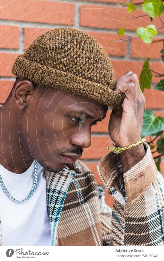 Stylish black man against brick wall street city style urban modern frown casual young male trendy outfit fashion ethnic hipster african american exterior