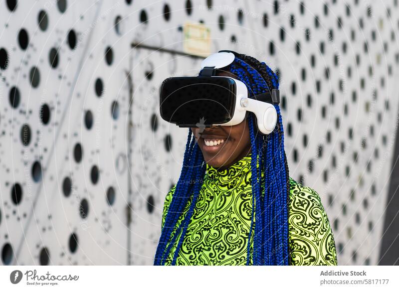 Black woman in VR headset in city vr virtual reality interact experience goggles street female ethnic black african american blue hair braid hairstyle trendy