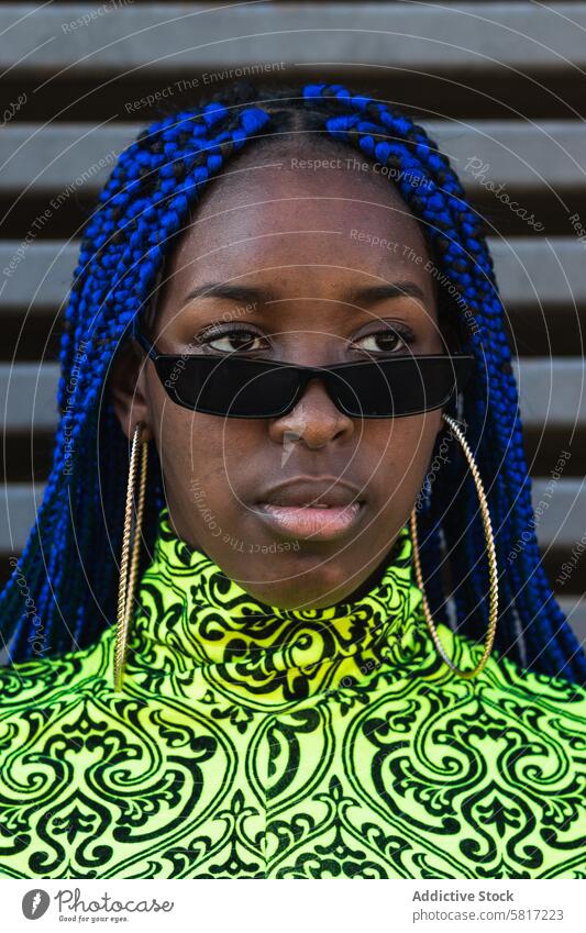 Stylish ethnic woman on city street blue hair braid hairstyle trendy outfit confident cool serious female african american black vivid determine appearance