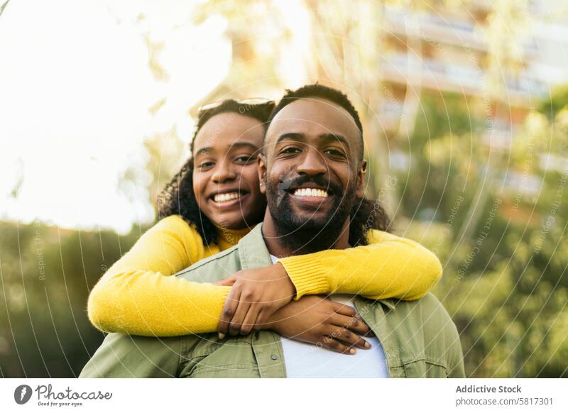 smiling black man giving piggyback ride to his girlfriend.front view happy fun people together carrying woman male family love portrait young african boy