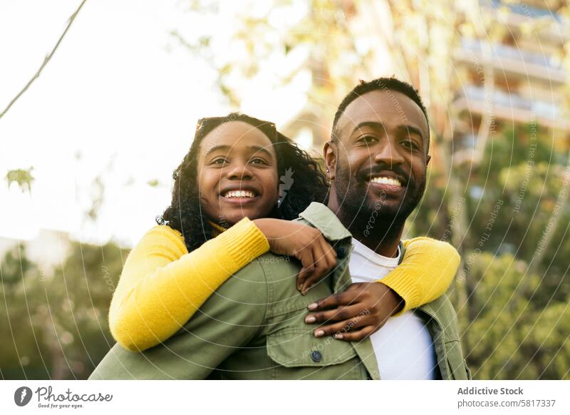Portrait of a smiling black man giving piggyback ride to his sister happy girl fun people together carrying woman male family love portrait young african boy