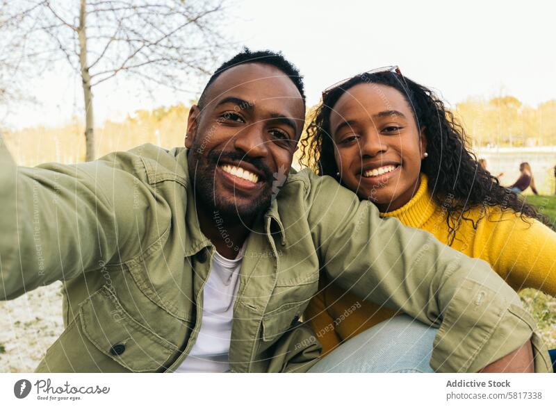afro american couple taking a selfie sitting in a park woman happy young african black people cheerful portrait female smiling boyfriend smartphone girlfriend