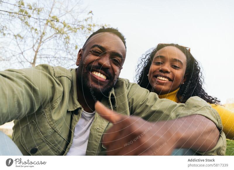 afro american couple taking a selfie sitting in a park woman happy young african black people cheerful portrait female smiling boyfriend smartphone girlfriend