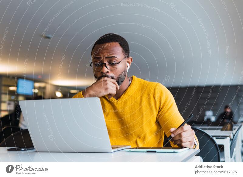 Black man working on laptop with tablet graphic tablet designer earphones using online internet office take note male black african american netbook