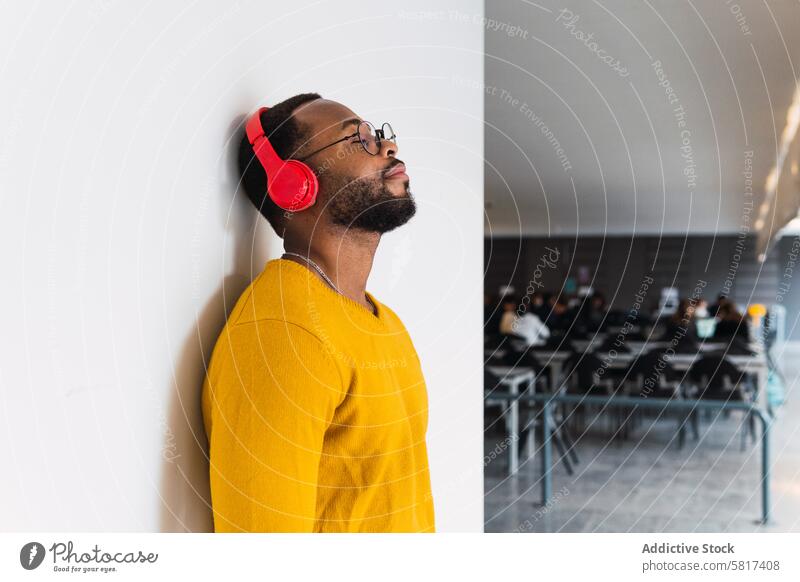 Black man listening to music in headphones using relax rest chill song meloman male black african american enjoy device thoughtful wireless eyes closed