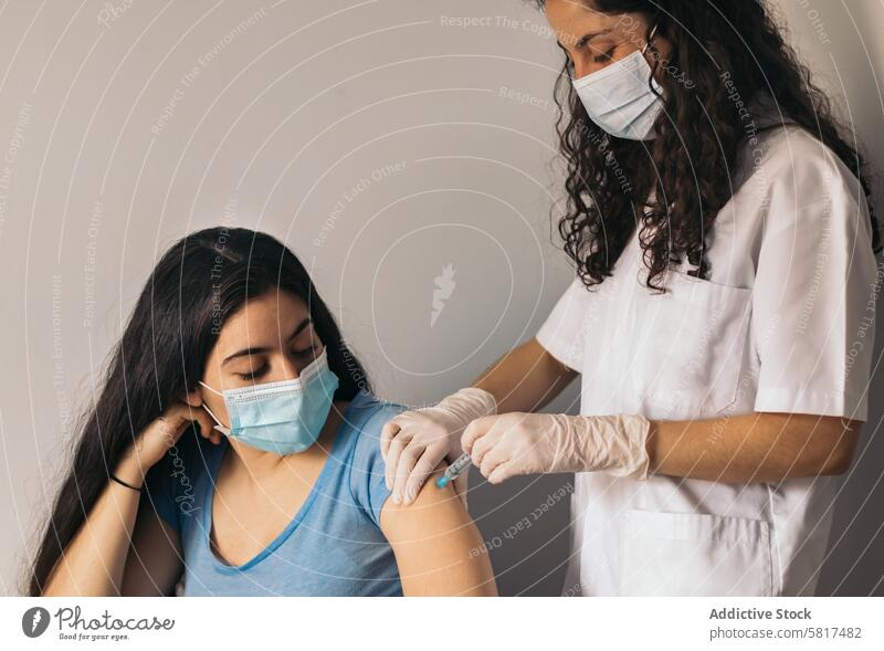 doctor makes vaccination to young woman with surgical mask patient medical injection health medicine clinic coronavirus prevention nurse vaccine shot protection