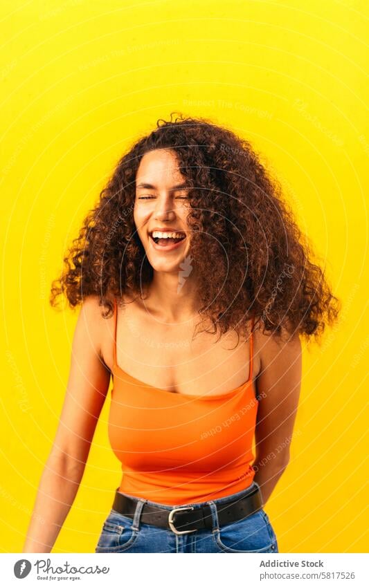 beautiful afro woman smiling and laughing portrait leaning on a yellow wall african black young attractive american casual cheerful beauty happy people female
