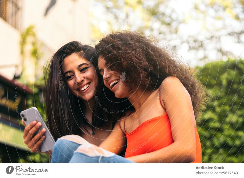 two beautiful women sitting using her mobiles female young happy technology phone smartphone together woman lifestyle looking people adult smiling girl cheerful