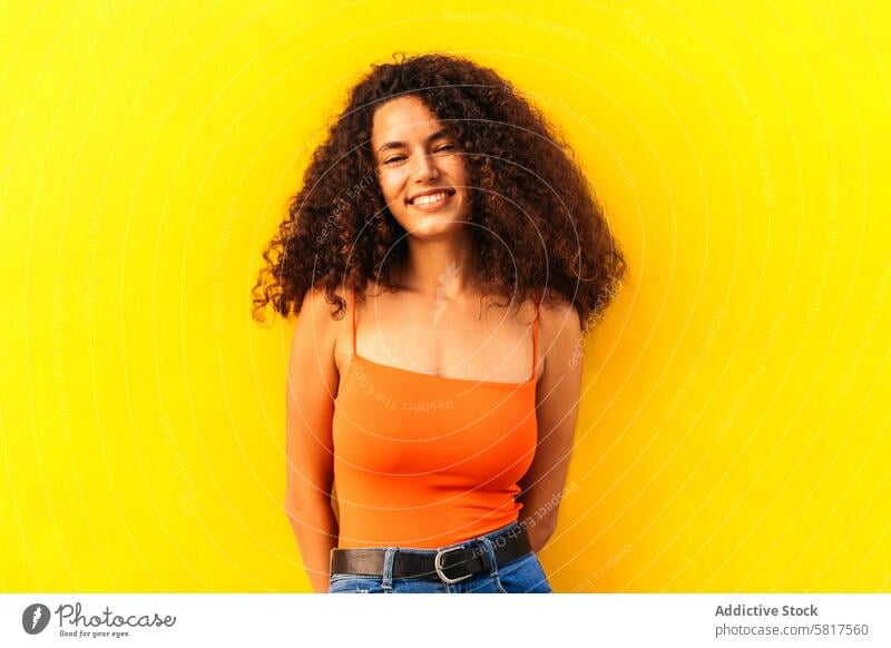 beautiful afro woman portrait leaning on a yellow wall african black young attractive american casual cheerful beauty happy people female looking girl curly