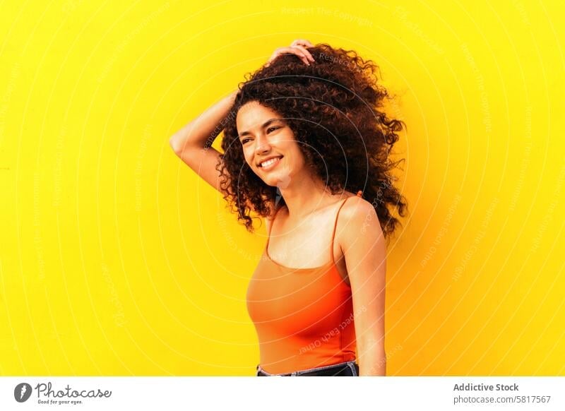 beautiful afro woman looking aside portrait leaning on a yellow wall african black young attractive american casual cheerful beauty happy people female girl