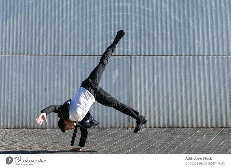 Ethnic businessman performing breakdance handstand on street break dance trick move entrepreneur formal suit male ethnic asian urban city executive manager