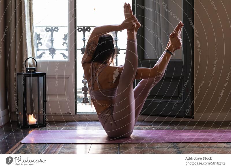 Unrecognizable woman performing Boat pose at home yoga stretch flexible wellbeing energy vitality balance legs raised talent boat pose practice wellness