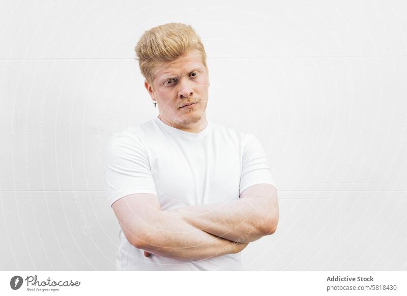 Monochrome: Portrait of an albino Latino man in white clothing against a white background. male guy blond face person young hair adult handsome albinism blonde