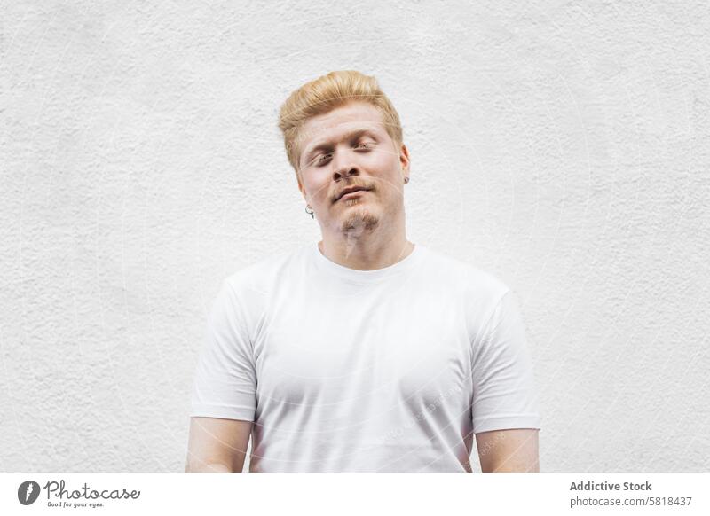 Monochrome: Portrait of an albino Latino man in white clothing against a white background. male guy blond face person young hair adult handsome albinism blonde
