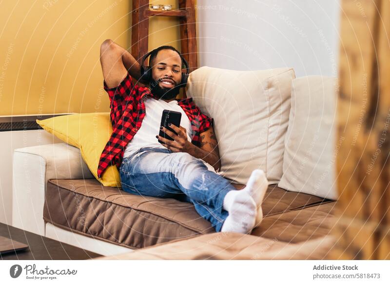 African american man relaxing using smartphone on the sofa at home black couch african american mobile technology internet happy communication cheerful adult