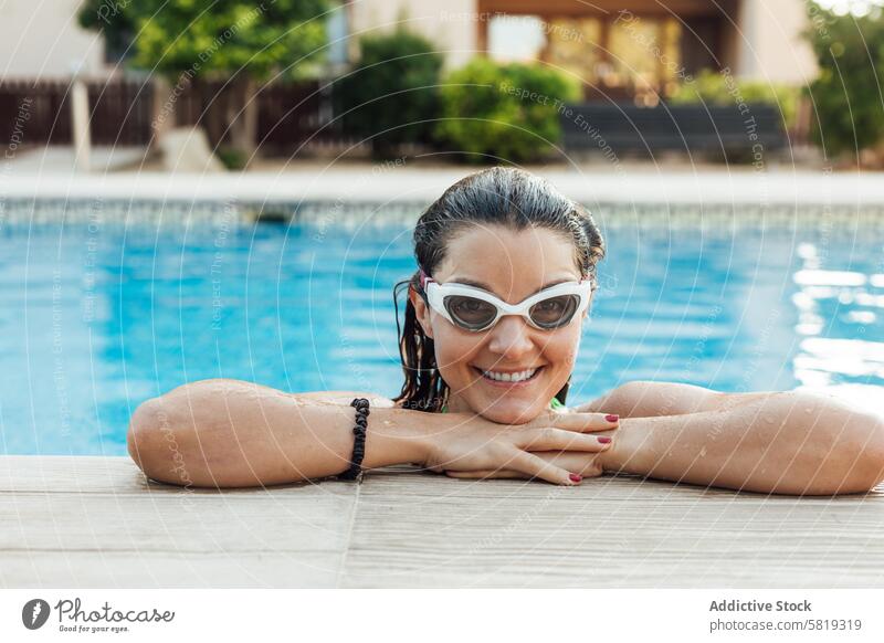 Woman enjoying a refreshing swim at a pool woman goggles smile sunny day edge enjoyment water leisure outdoor relaxation fun happy cheerful wet swimwear sport