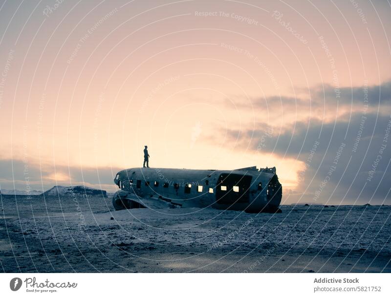 Person on abandoned airplane wreckage in Iceland at dusk iceland desolate figure silhouette landscape sky pastel solitary travel adventure exploration sunset