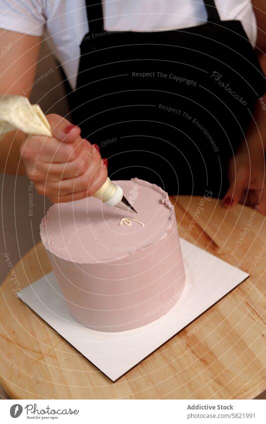 Icing a cake with precision and care person decorating icing piping bag pink detail adornment dessert baking confectionery pastry chef skill artistry frosting