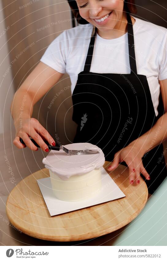 Woman frosting a cake with precision and joy woman baking kitchen decorating spatula smile confectionery pastry dessert icing cook apron culinary hobby homemade