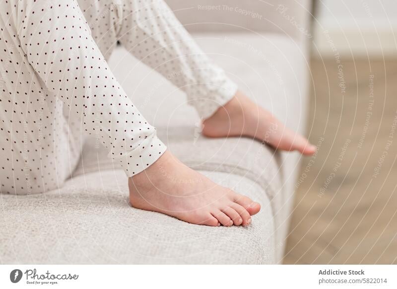 Close-up of child's bare feet in pajamas at home barefoot sofa fabric texture close-up sitting comfort cozy relax casual indoor body part skin care health