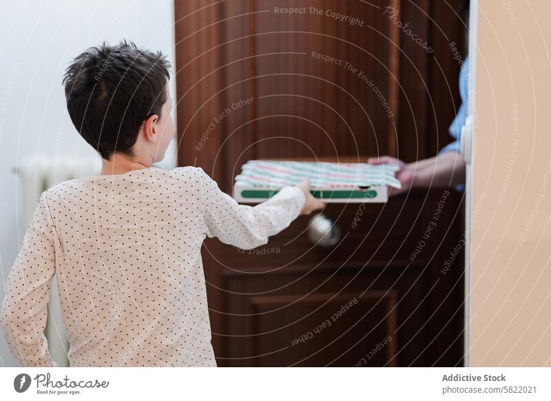 Young boy at home receiving a stack of folded towels delivery door domestic striped clean house household chore responsibility care service hygiene fabric