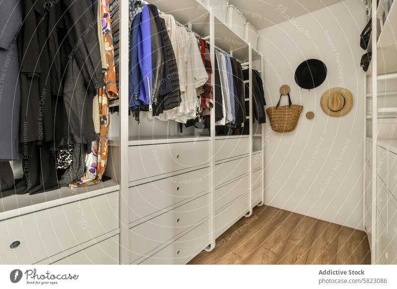 Neatly organized walk-in closet with an array of clothes and accessories organization accessory hanger drawer shelving wooden floor design functional neat white