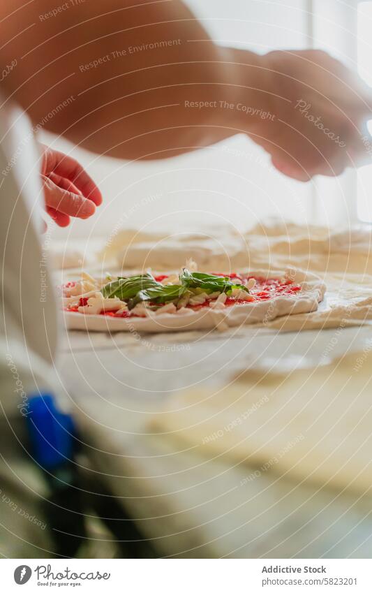 Preparing Fresh Pizza in a Pizzeria pizzeria chef pizza topping tomato basil cheese dough kitchen culinary preparation food fresh cooking anonymous craft