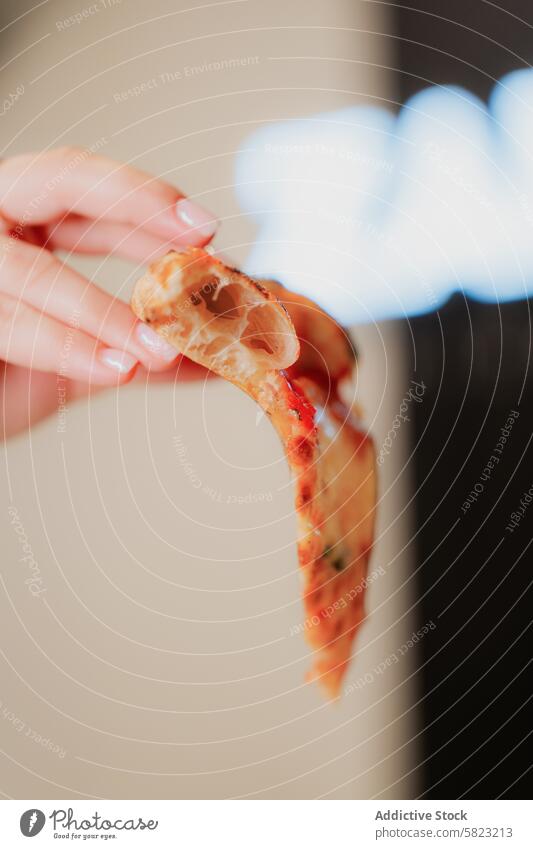 Slice of pizza held in a person's hand with blurry background slice cheese hold food meal italian crust pizzeria blurred anonymous snack lunch dinner delicious