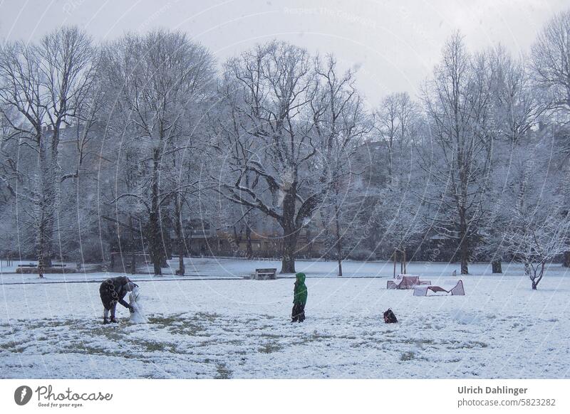 Park in winter with snowfall. Adult and child building a snowman Winter game activity Outdoors fun Infancy Playing out chill Movement Parent and child active